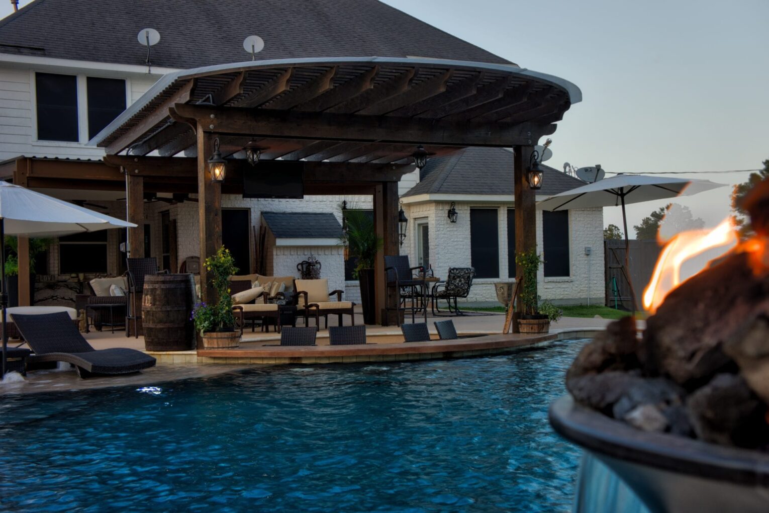 A pool with an outdoor dining area and a gazebo.
