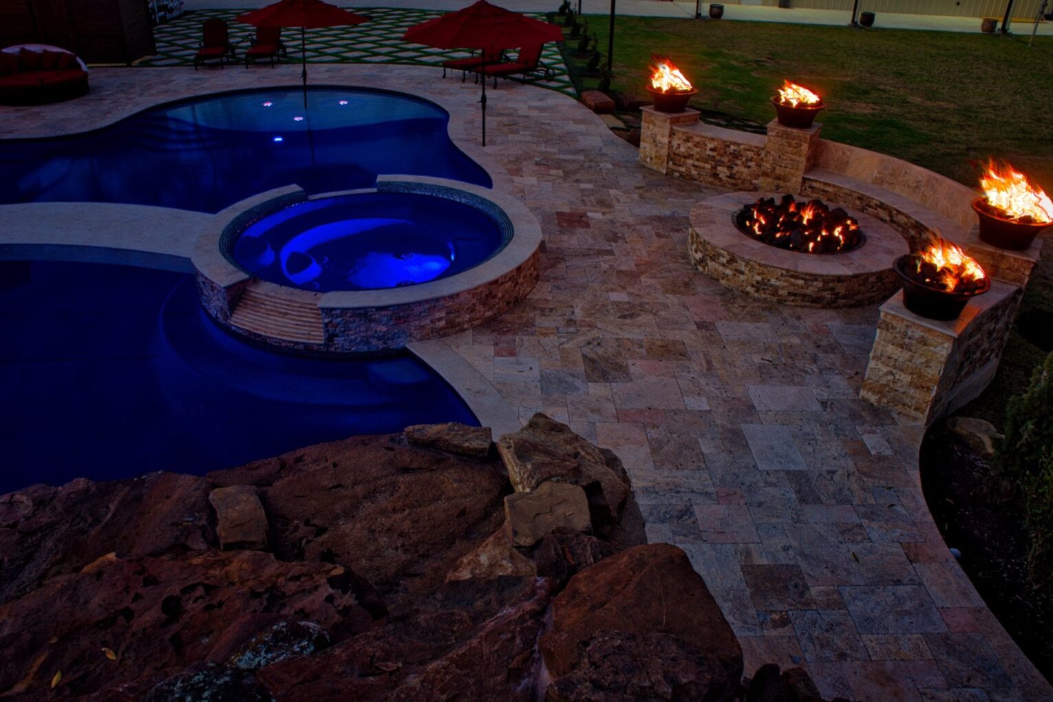 A pool with a fire pit and rocks around it