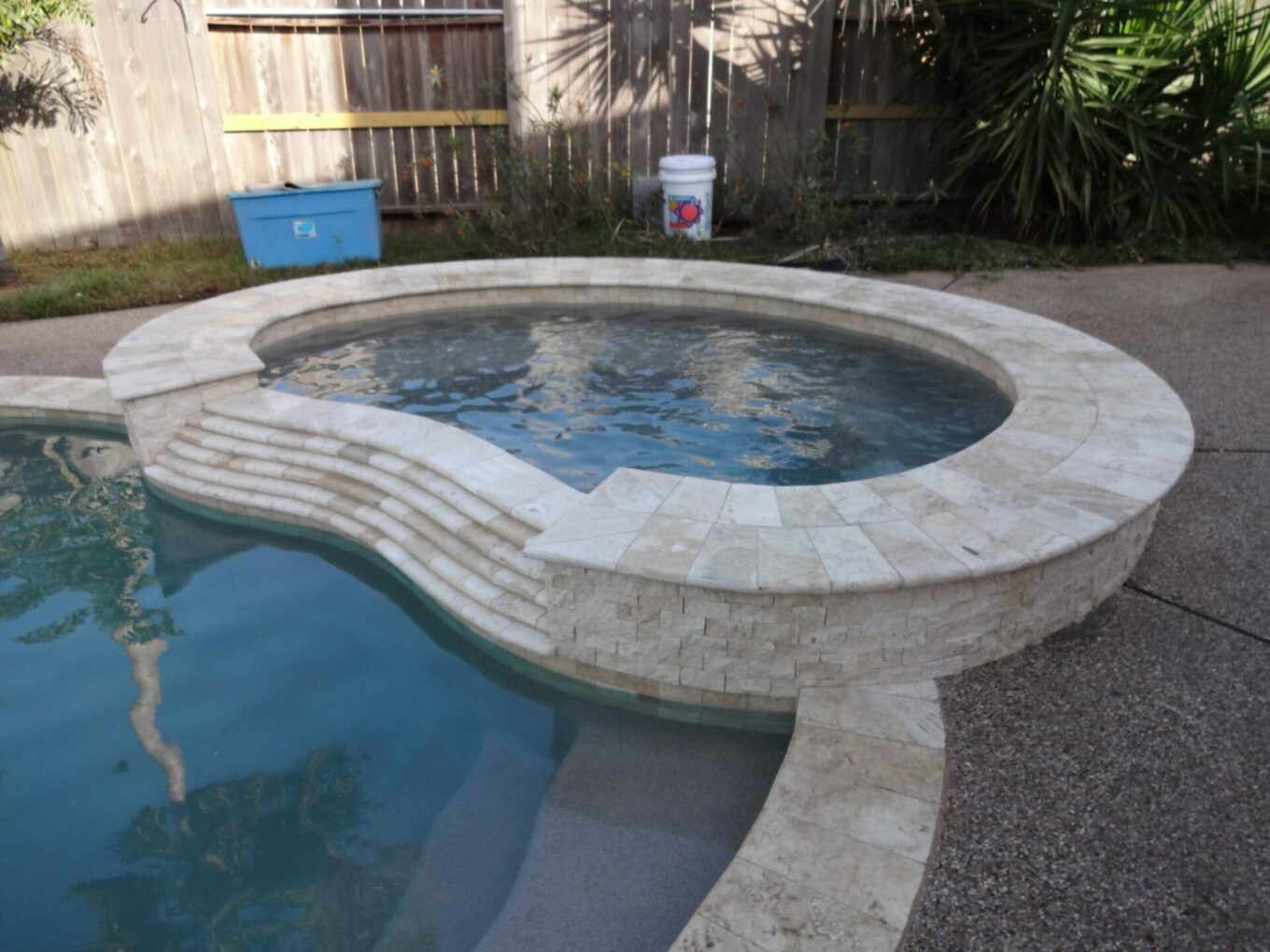 A pool with a stone surround and a brick edge.