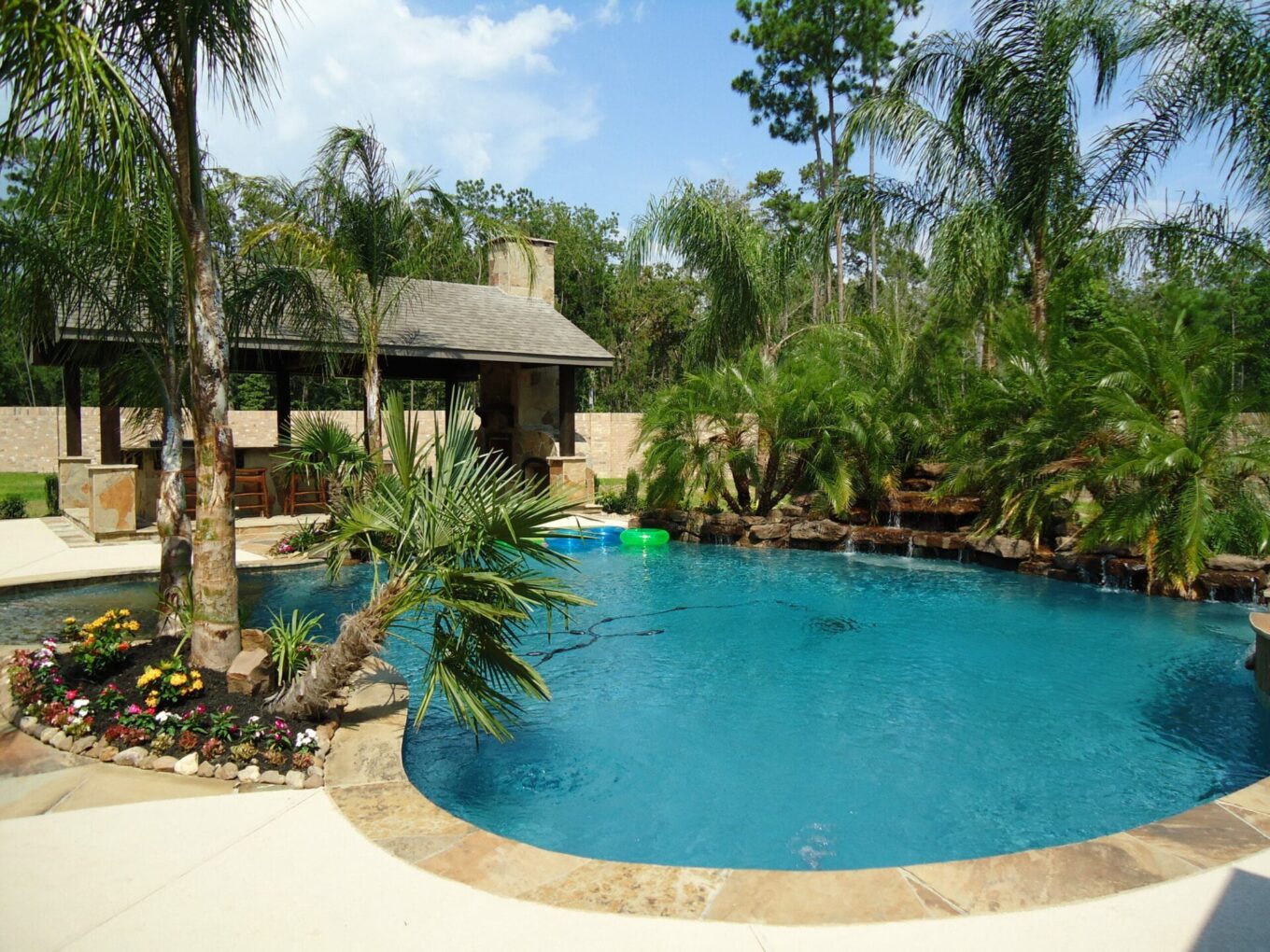 A pool with palm trees and a house in the background.
