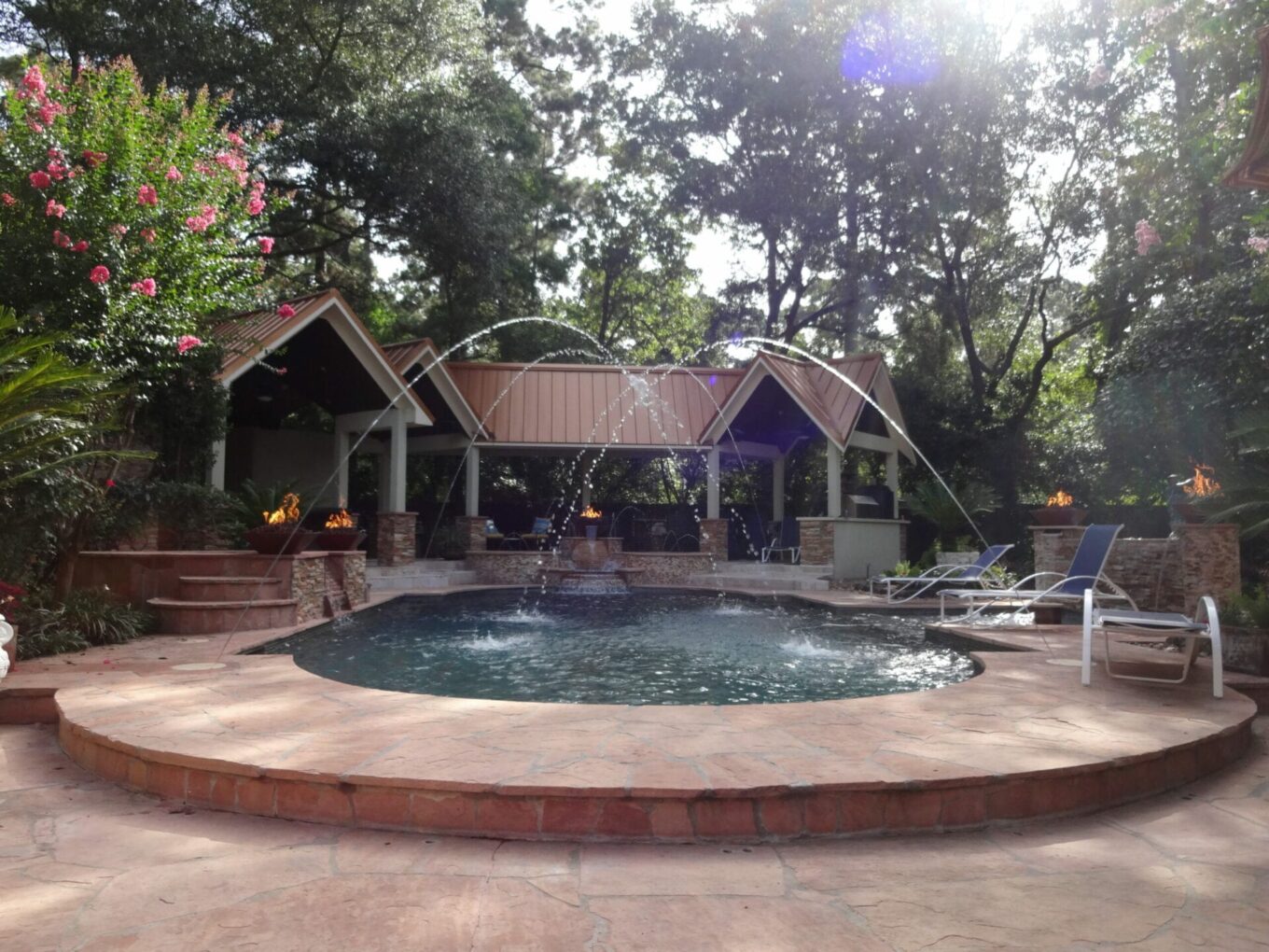 A large pool with water jets and a gazebo.