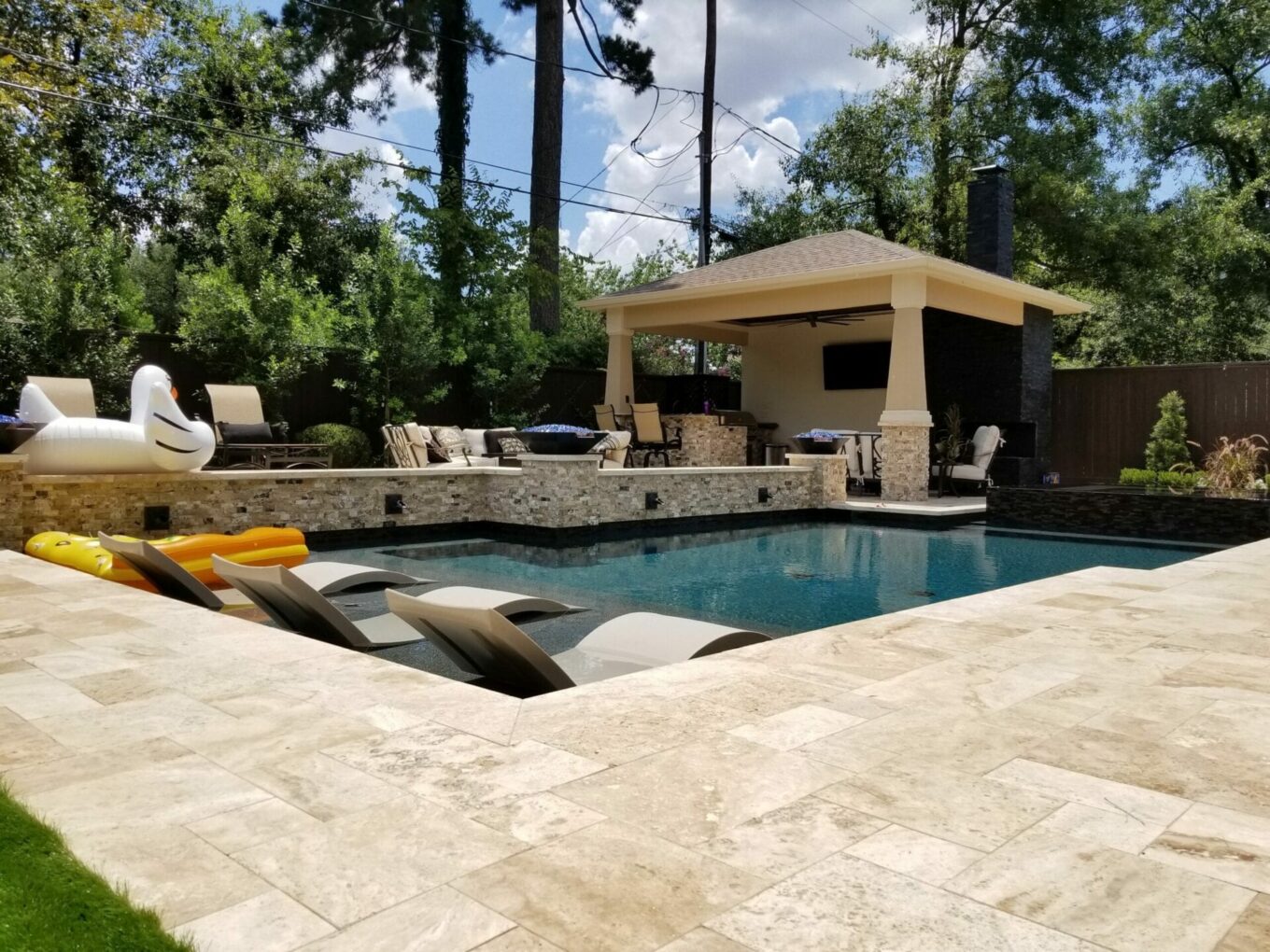 A pool with an outdoor grill and seating area.