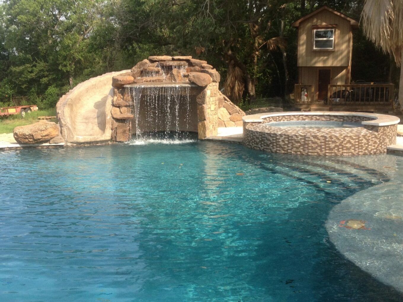 A pool with a waterfall and rock wall