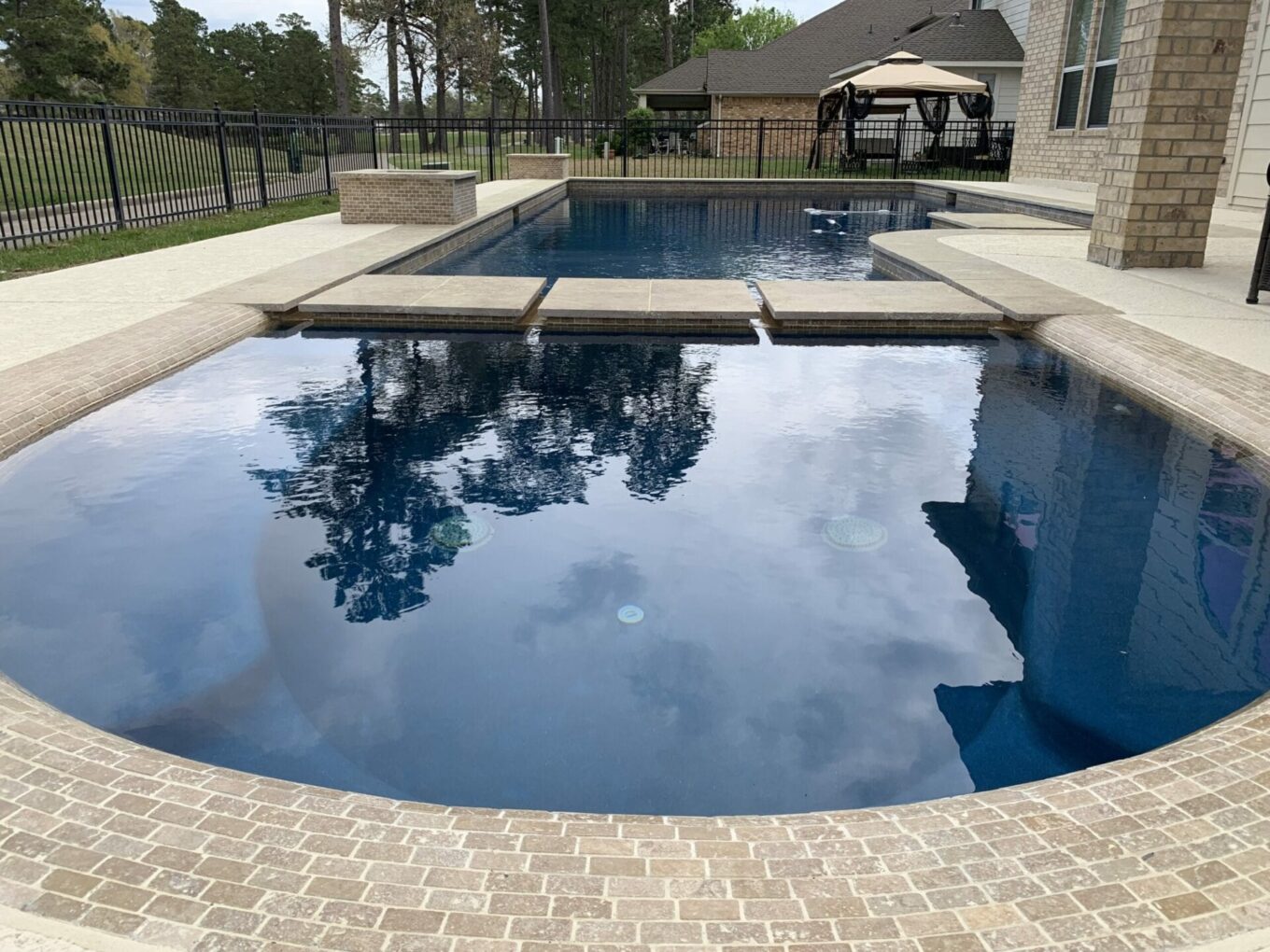A pool with a brick floor and a blue water