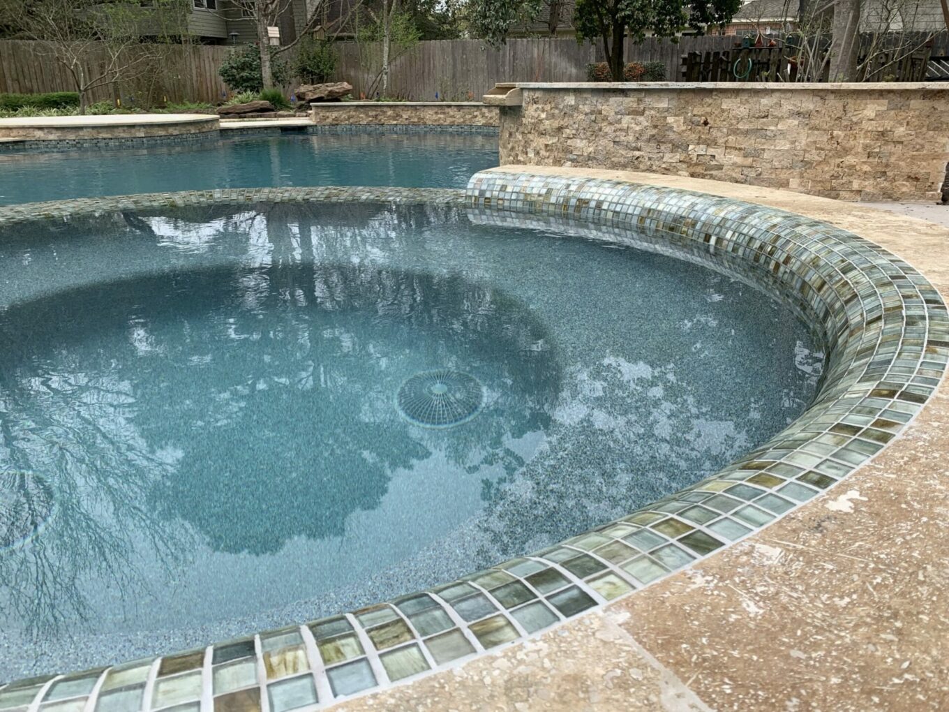 A pool with a waterfall and stone surround.