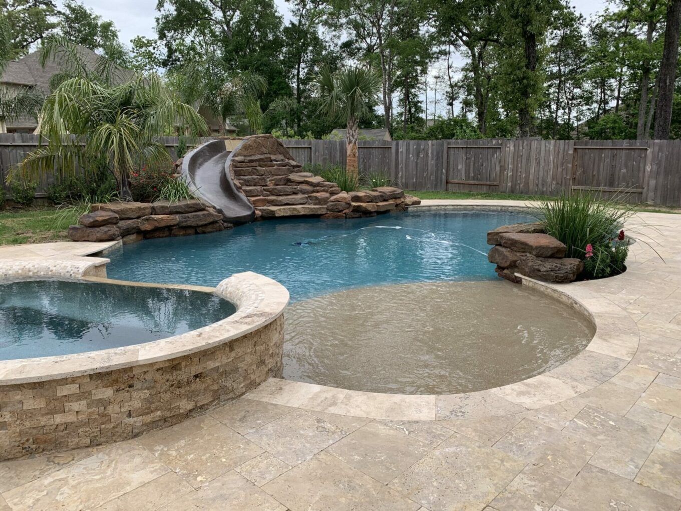 A pool with a slide and a rock wall