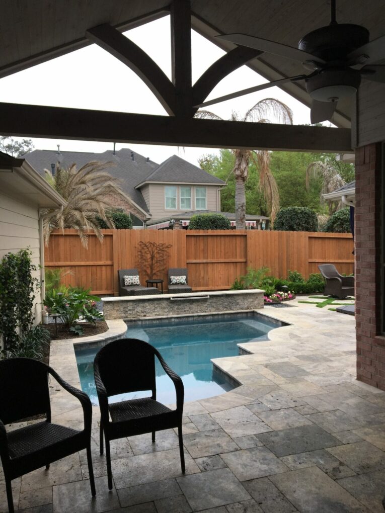 A backyard with an outdoor pool and patio furniture.