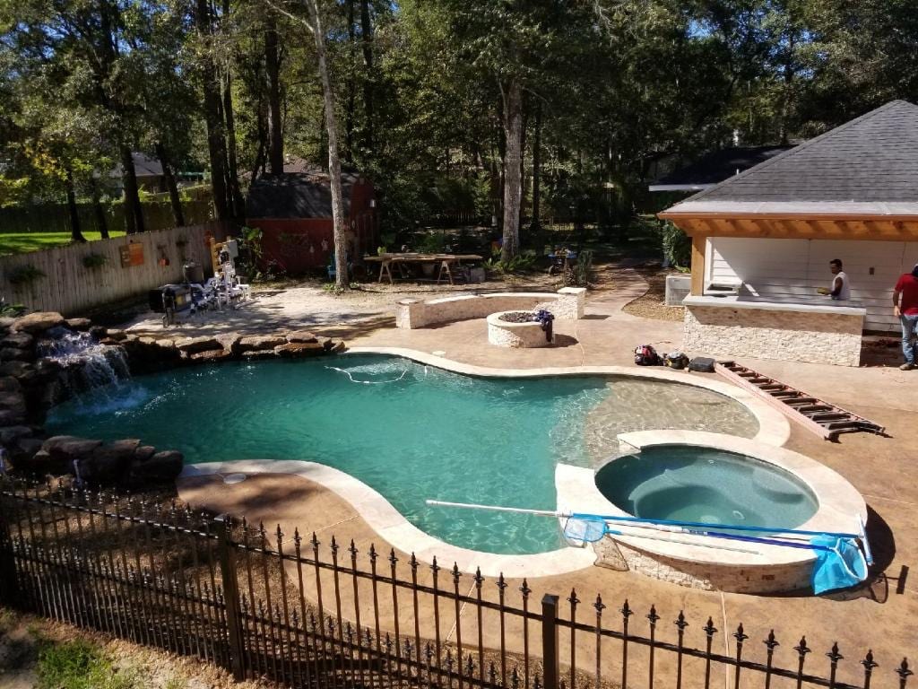 A pool with a large stone wall and a fence.
