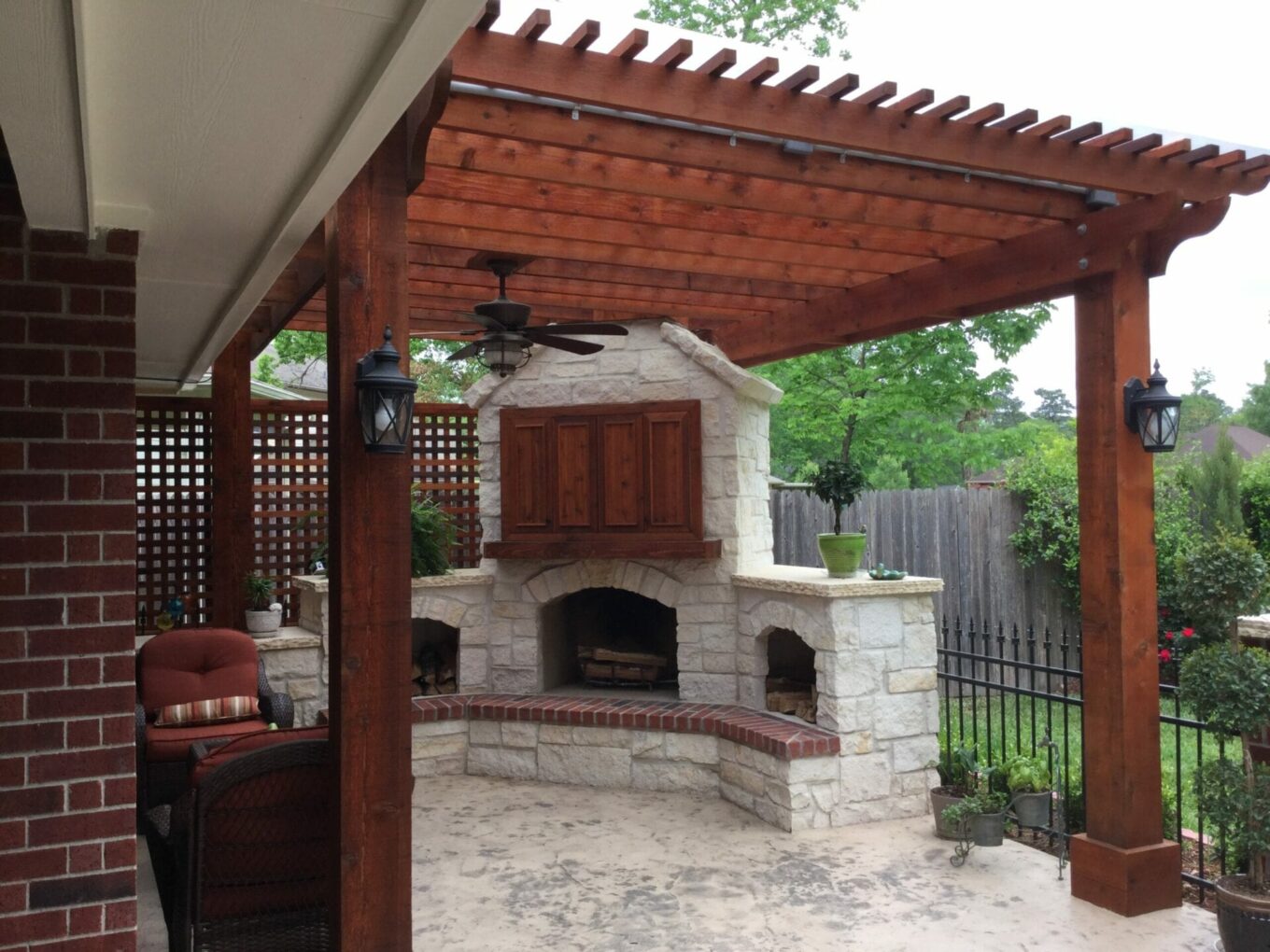A patio with an outdoor fireplace and pergola.