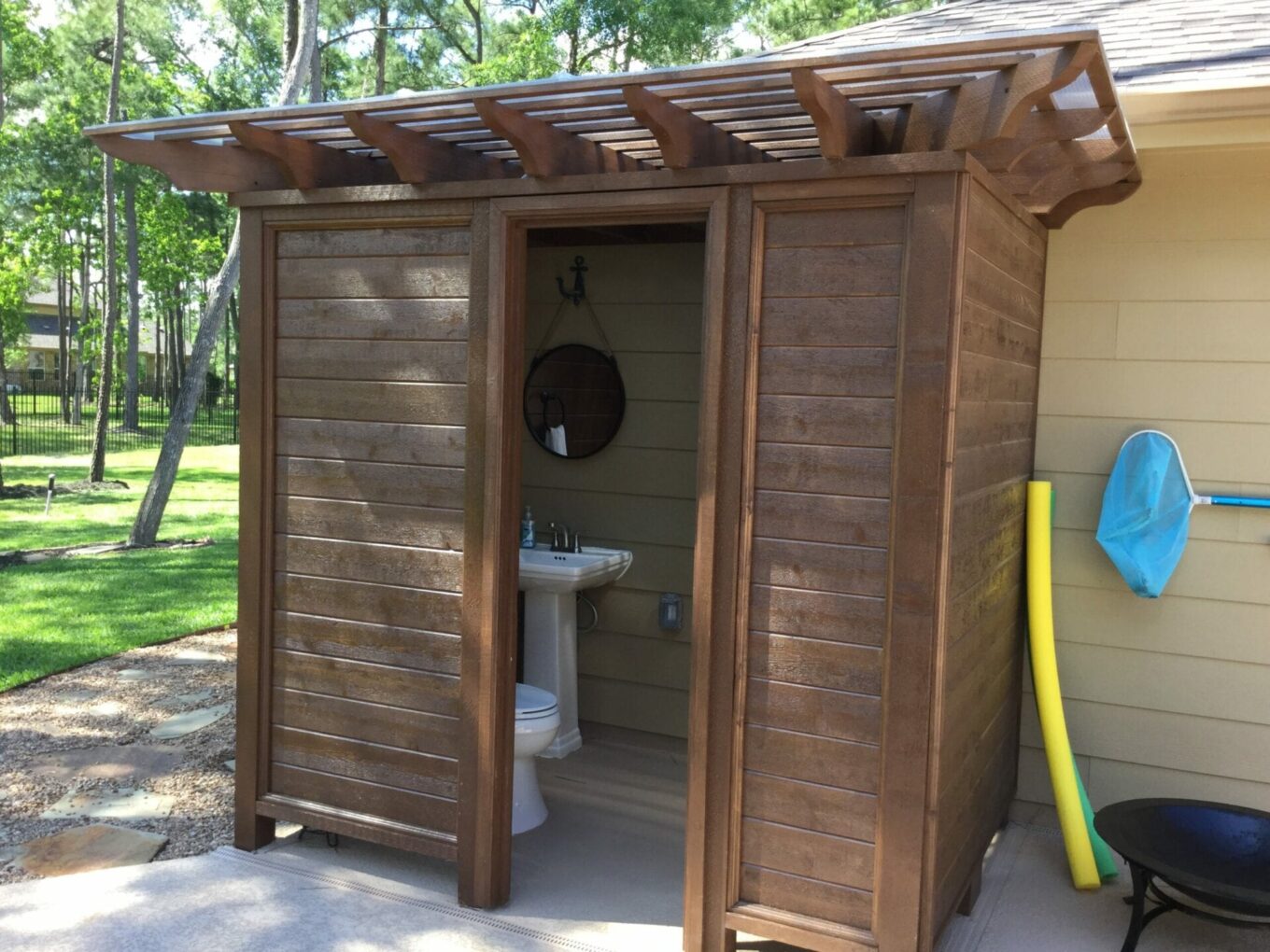 A wooden outhouse with a toilet and sink.