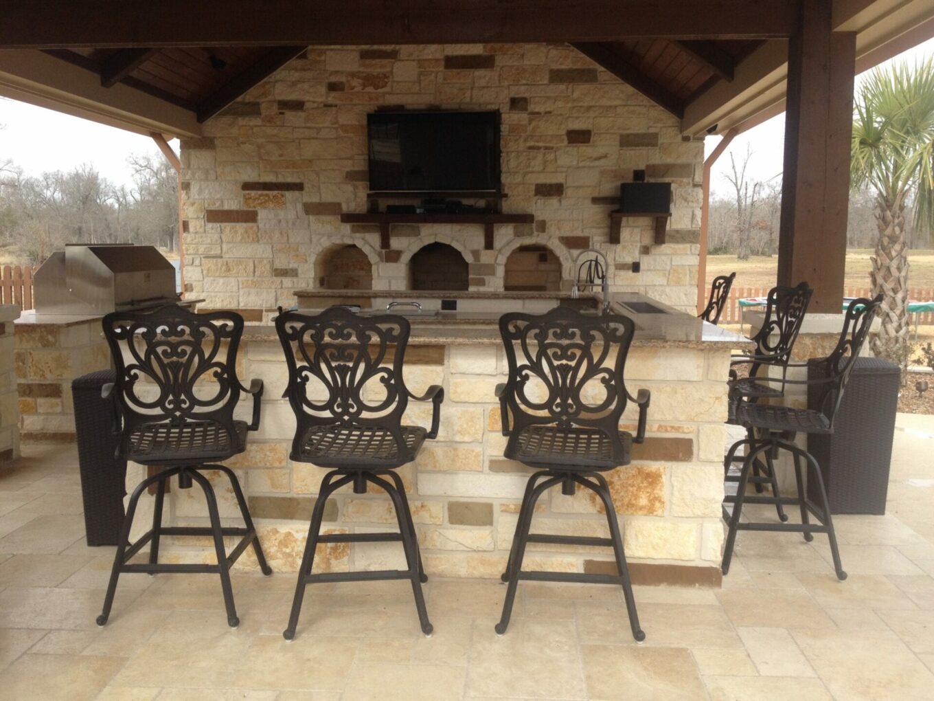 A group of chairs and stools in front of an outdoor fireplace.