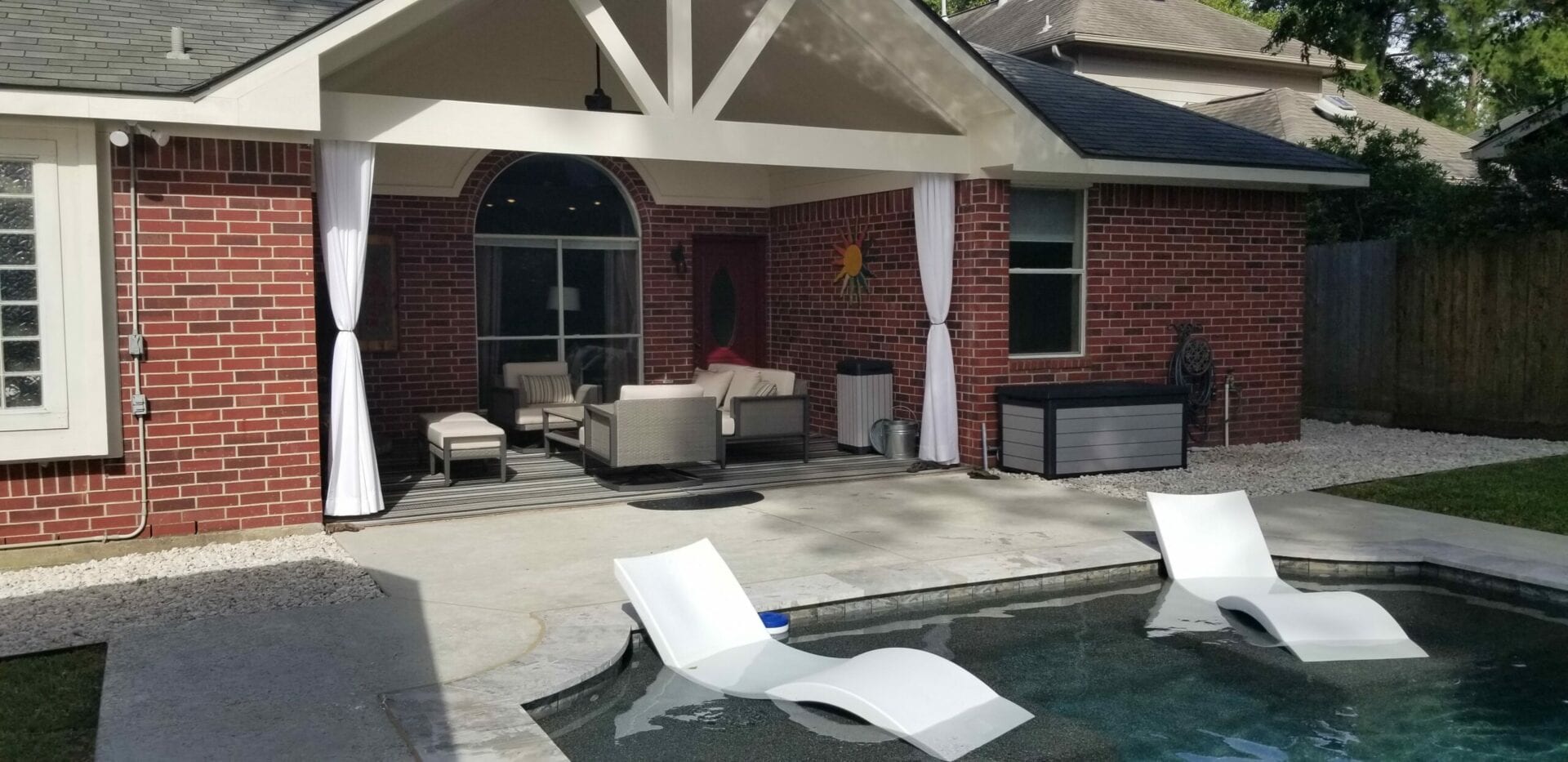 A pool with chairs and tables in the back yard