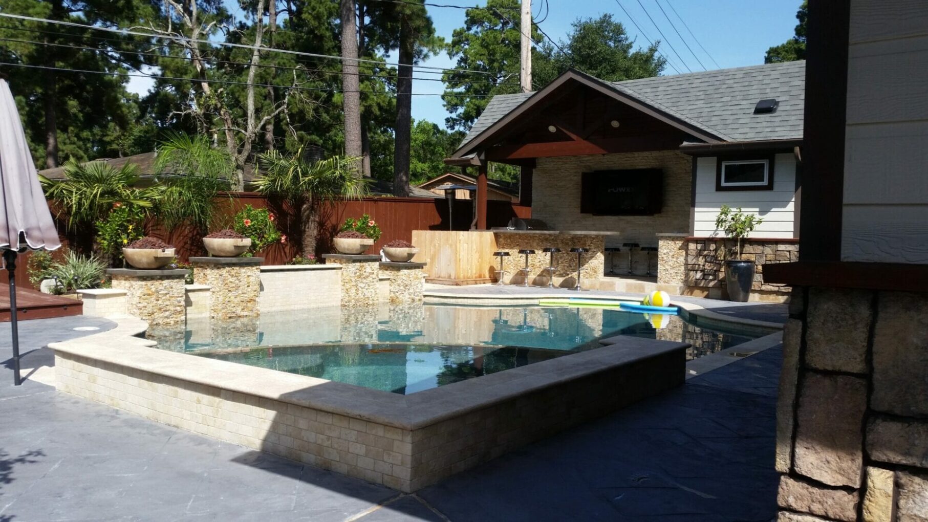 A pool with a stone wall and a large outdoor area.