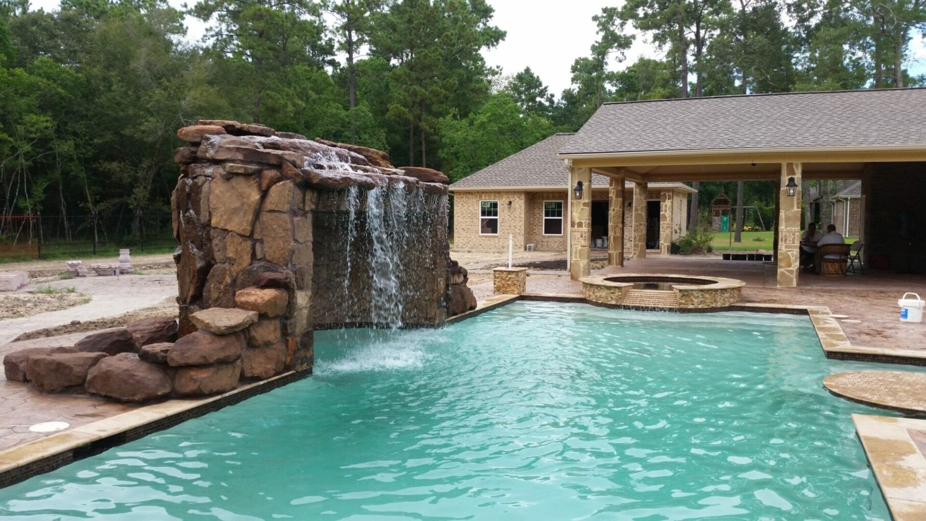 A pool with a waterfall and a stone wall.