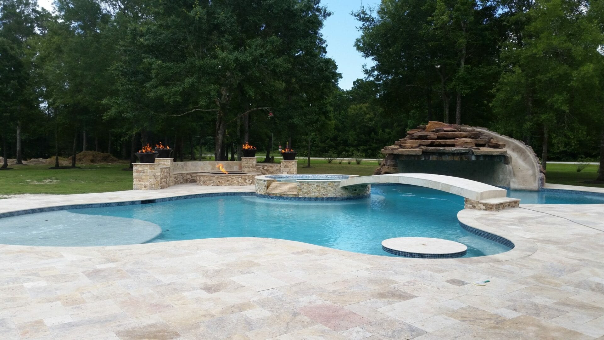 A pool with a rock wall and steps leading to the pool.