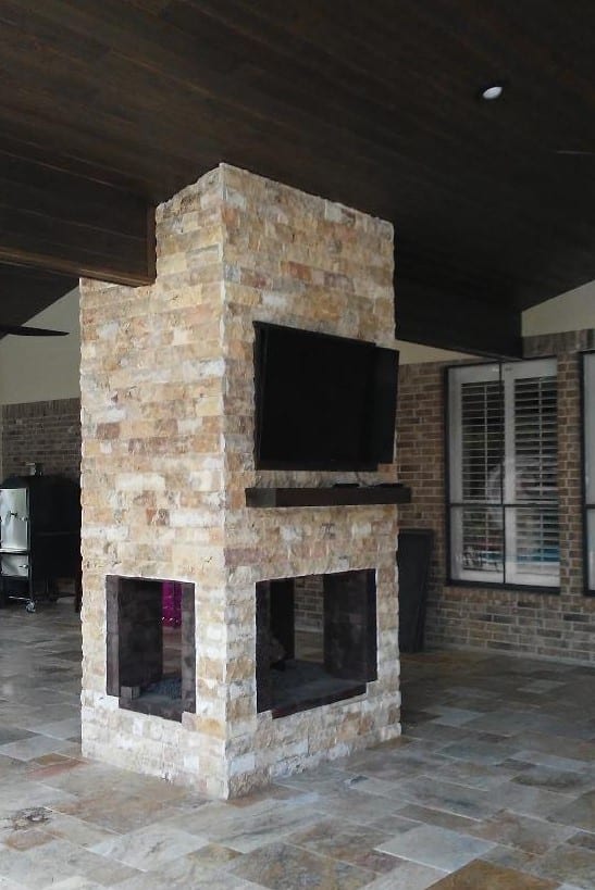 A stone fireplace with a television mounted on the side.