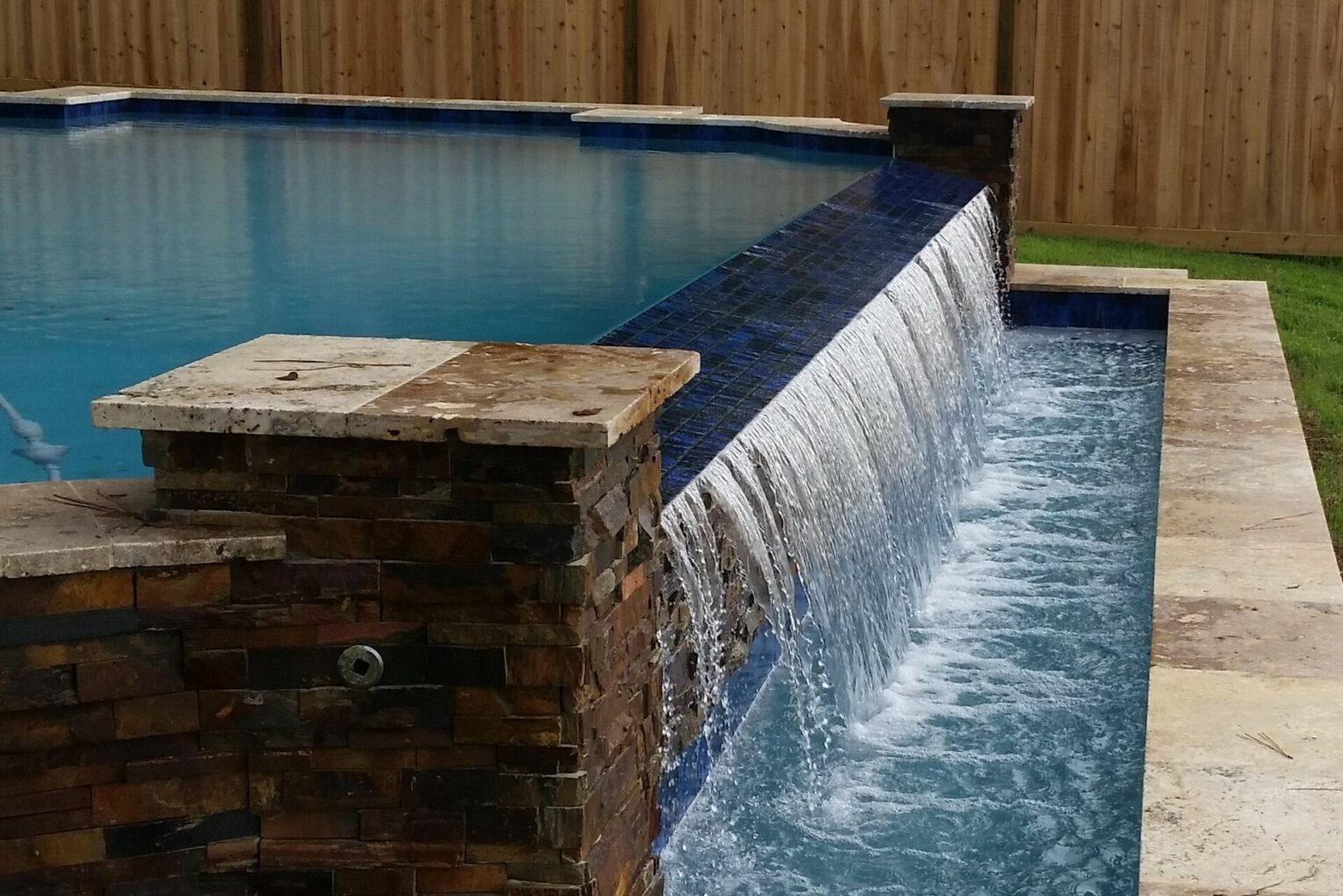 A pool with water flowing over the edge of it.