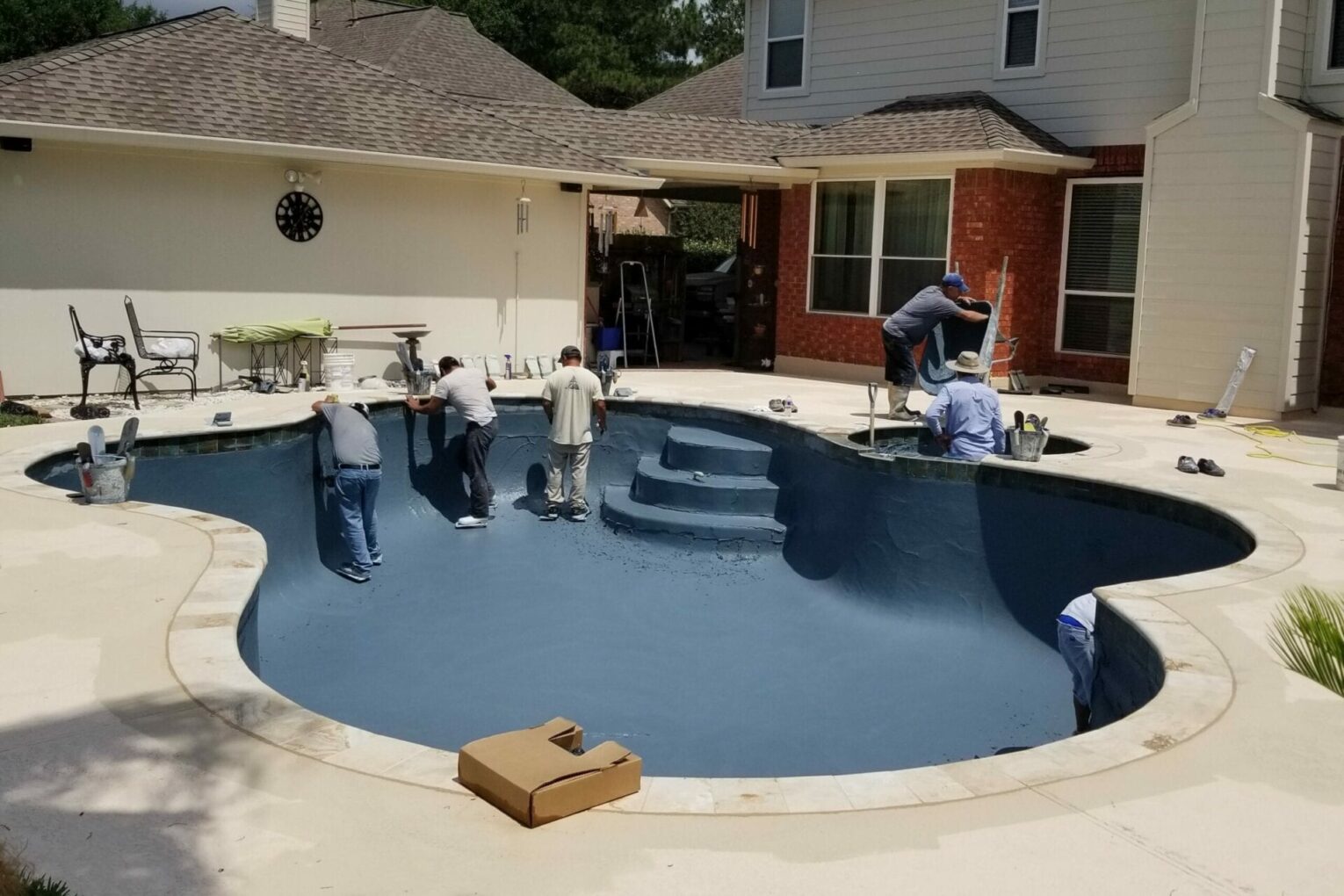 A group of people standing around an empty pool.